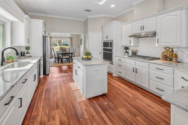 kitchen with visible vents, under cabinet range hood, white cabinets, stainless steel appliances, and a sink