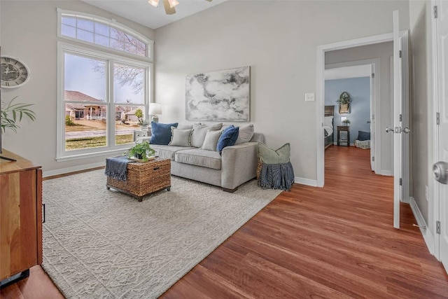 living area featuring ceiling fan, baseboards, and wood finished floors