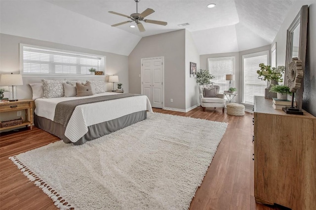 bedroom featuring vaulted ceiling, multiple windows, wood finished floors, and visible vents