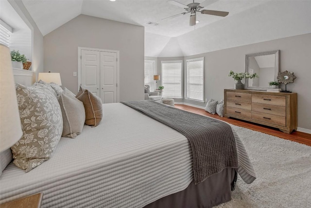 bedroom featuring visible vents, a ceiling fan, wood finished floors, a closet, and vaulted ceiling