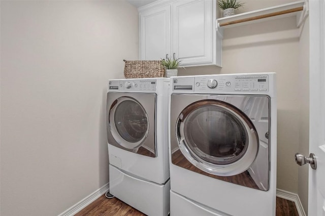 laundry room with wood finished floors, cabinet space, baseboards, and washing machine and clothes dryer