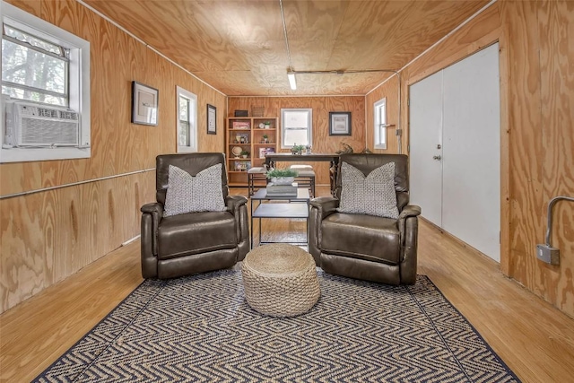 living area featuring cooling unit, wood walls, built in shelves, and wood finished floors