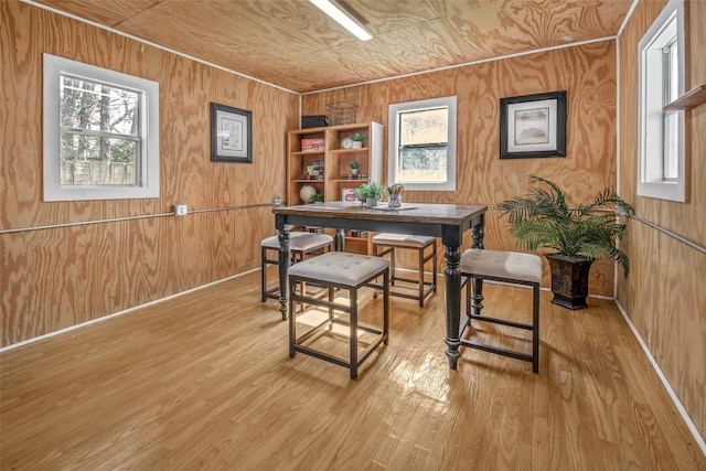 dining area with light wood finished floors, wood walls, and baseboards