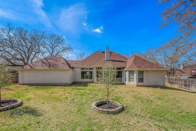 rear view of property featuring a yard, a fenced backyard, and a chimney