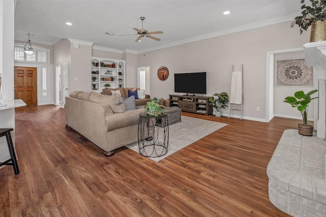 living area featuring ornamental molding, a ceiling fan, built in features, wood finished floors, and baseboards