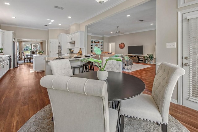 dining area with dark wood finished floors, visible vents, recessed lighting, and ornamental molding