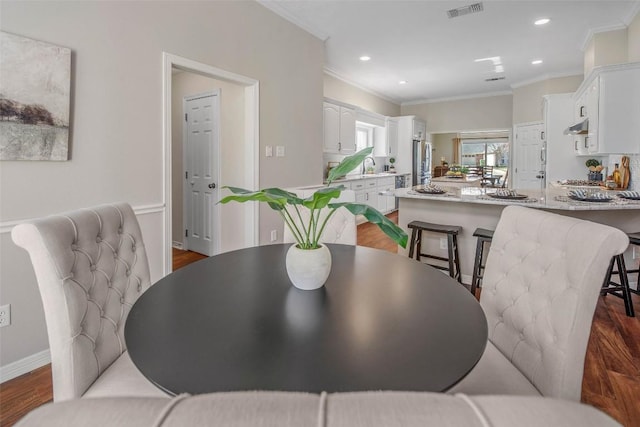 dining area featuring dark wood finished floors, crown molding, recessed lighting, and visible vents