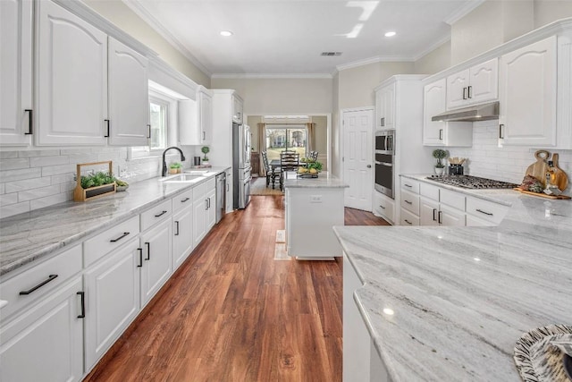 kitchen with ornamental molding, appliances with stainless steel finishes, white cabinets, and a sink