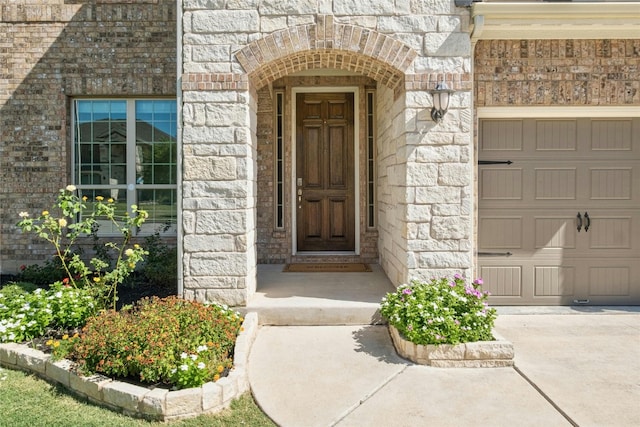 doorway to property featuring brick siding, stone siding, and a garage