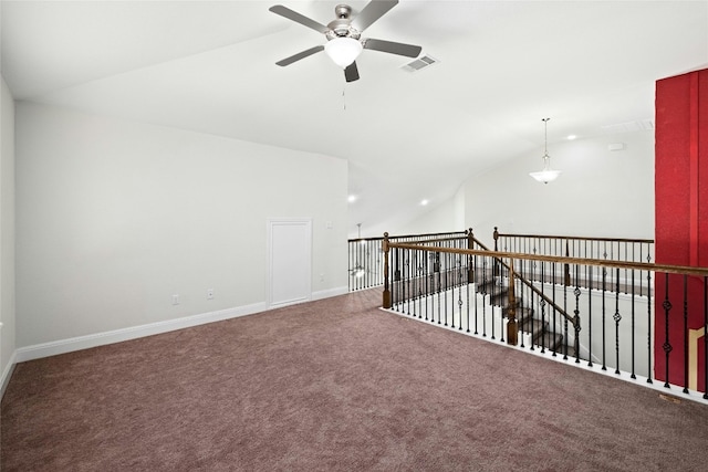 carpeted empty room featuring lofted ceiling, baseboards, visible vents, and ceiling fan