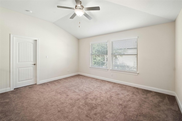 carpeted spare room with vaulted ceiling, a ceiling fan, and baseboards