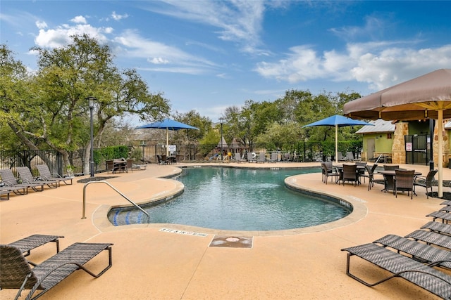 community pool with a patio and fence