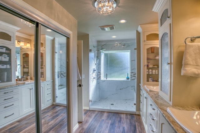 full bathroom with a marble finish shower, visible vents, vanity, and wood finished floors