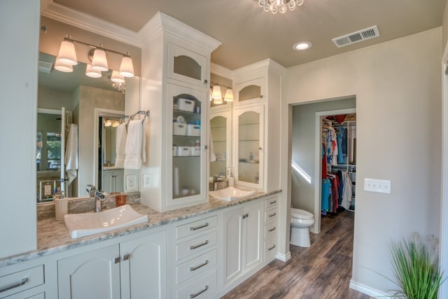 bathroom with a sink, visible vents, wood finished floors, and double vanity