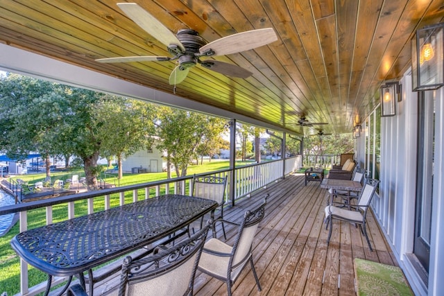 wooden deck with a lawn, outdoor dining area, and ceiling fan