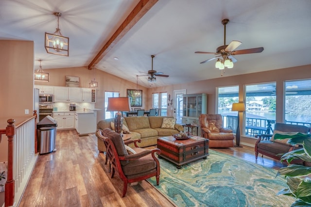 living area with ceiling fan with notable chandelier, vaulted ceiling with beams, and light wood-type flooring