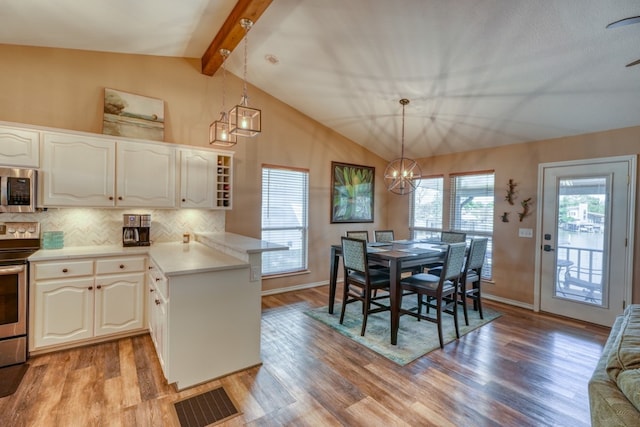 kitchen with stainless steel appliances, visible vents, a peninsula, and vaulted ceiling with beams