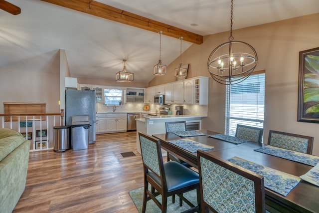 dining space with lofted ceiling with beams, a chandelier, and wood finished floors