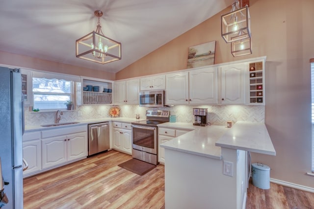 kitchen with white cabinetry, a peninsula, appliances with stainless steel finishes, and a sink