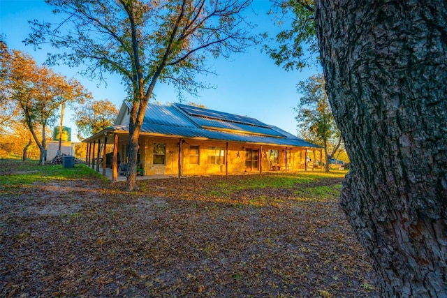 rear view of house with metal roof and roof mounted solar panels