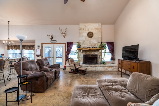 living room with ceiling fan with notable chandelier, a fireplace, french doors, and a healthy amount of sunlight