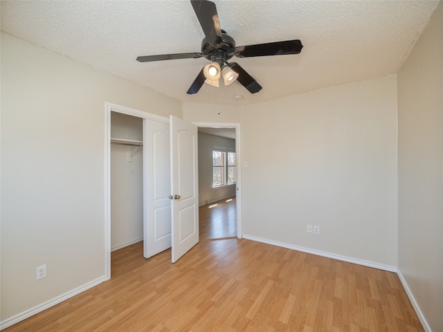 unfurnished bedroom featuring a closet, baseboards, a textured ceiling, and light wood finished floors