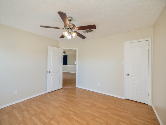 unfurnished room with visible vents, a textured ceiling, light wood-type flooring, and baseboards