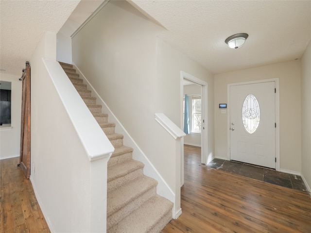 foyer featuring a barn door, wood finished floors, and a textured ceiling