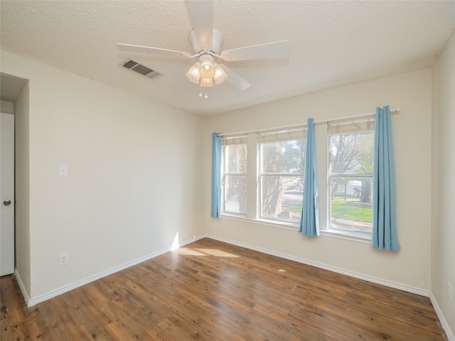 unfurnished room with visible vents, a ceiling fan, a textured ceiling, wood finished floors, and baseboards