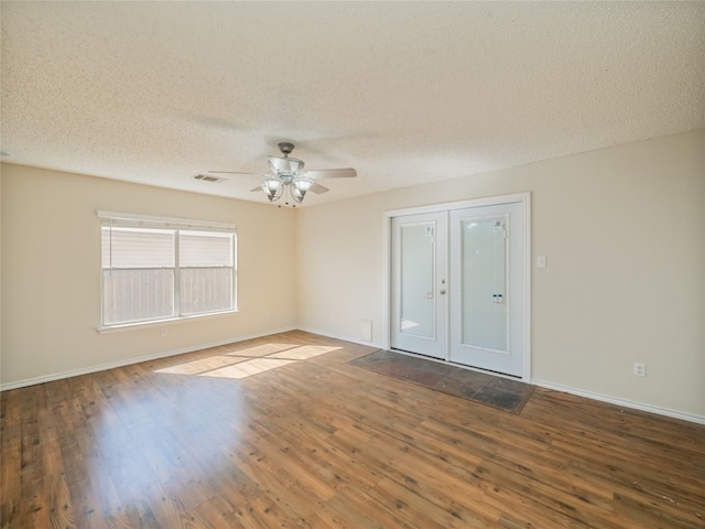 empty room with wood finished floors, visible vents, and a textured ceiling