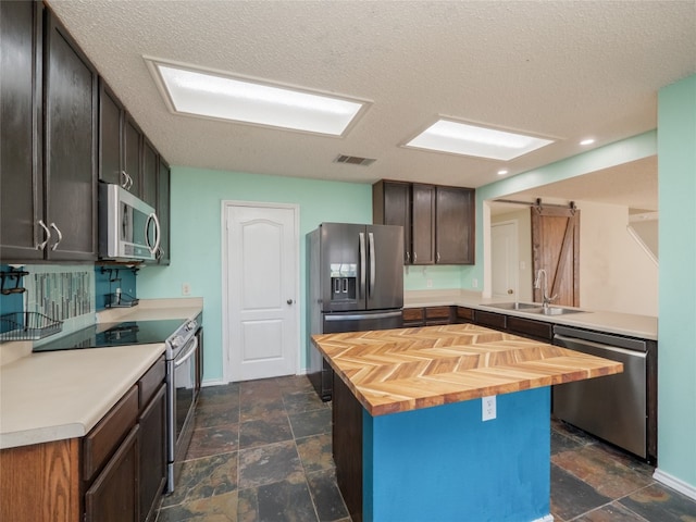 kitchen featuring visible vents, a sink, stainless steel appliances, a barn door, and butcher block counters