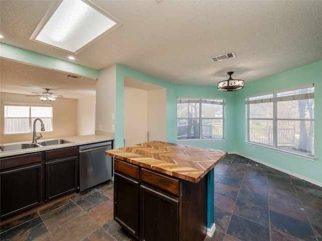 kitchen featuring visible vents, a sink, stainless steel dishwasher, stone tile floors, and butcher block counters