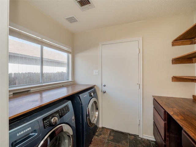 laundry room featuring visible vents, stone finish flooring, a textured ceiling, laundry area, and washing machine and clothes dryer