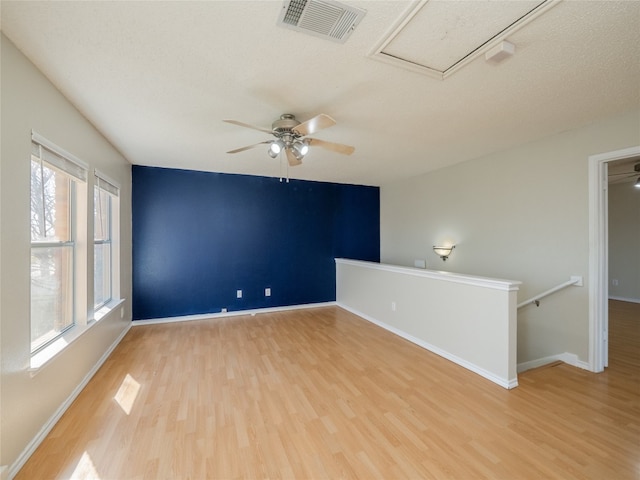 unfurnished room with attic access, baseboards, visible vents, and light wood-type flooring