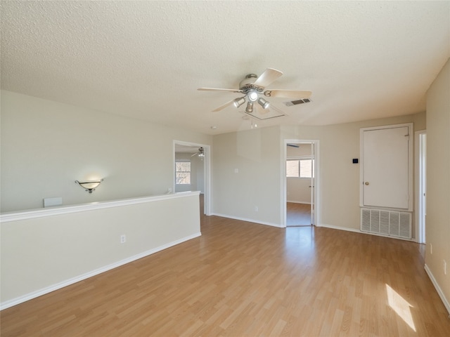 unfurnished room with ceiling fan, visible vents, and light wood-style flooring