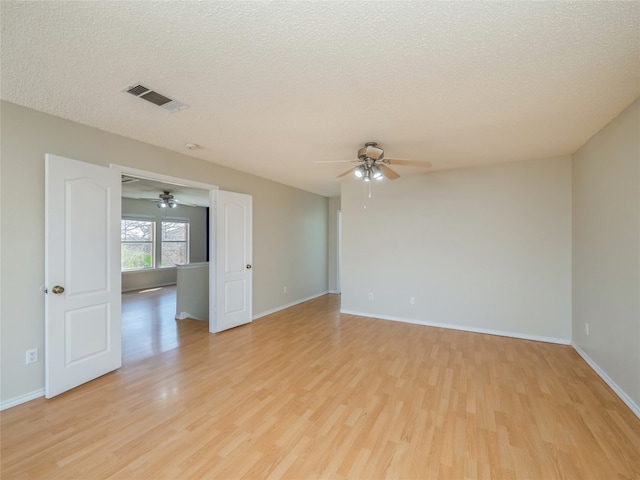 unfurnished room with visible vents, light wood-style flooring, a textured ceiling, and baseboards