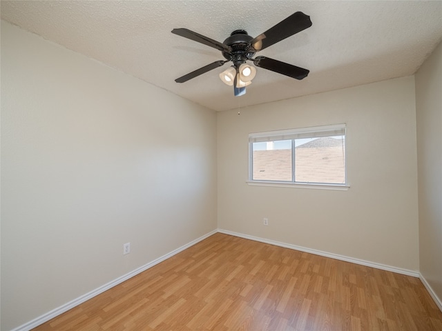 empty room featuring a textured ceiling, light wood-type flooring, and baseboards