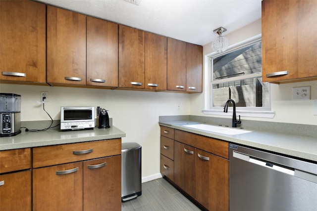 kitchen with baseboards, light countertops, stainless steel dishwasher, brown cabinetry, and a sink