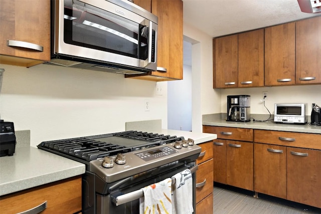 kitchen with brown cabinetry, stainless steel appliances, and light countertops