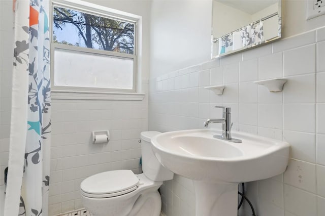 full bathroom featuring a shower with shower curtain, tile walls, toilet, and a wainscoted wall