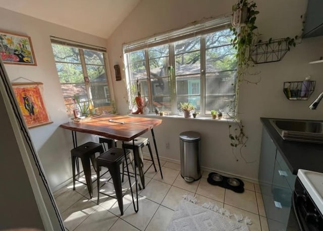 dining room with lofted ceiling, light tile patterned floors, and baseboards