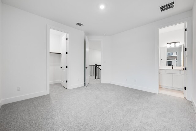 1821 Novara Trl, Leander, TX 78641 - unfurnished bedroom with a walk in closet, baseboards, light carpet, ensuite bath, and recessed lighting