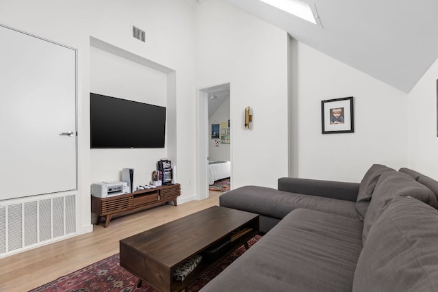 living room with visible vents, light wood finished floors, and vaulted ceiling