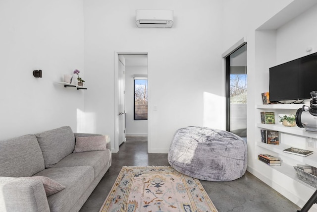 living room featuring a wealth of natural light, an AC wall unit, concrete floors, and baseboards