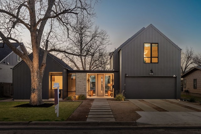 modern inspired farmhouse with a garage, concrete driveway, and a front lawn