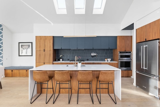 kitchen with light wood-type flooring, stainless steel appliances, a breakfast bar, and decorative backsplash