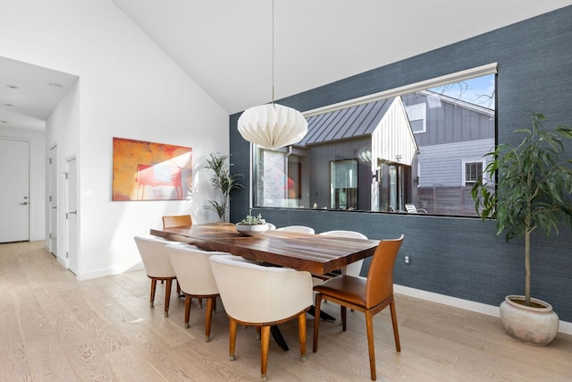 dining area with wood finished floors, baseboards, and high vaulted ceiling