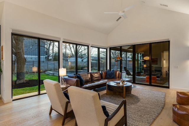 sunroom / solarium with visible vents, a healthy amount of sunlight, a ceiling fan, and vaulted ceiling