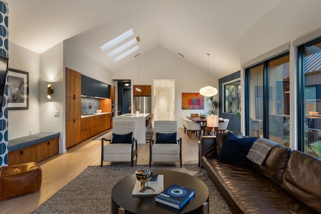 living area featuring a skylight, high vaulted ceiling, and light wood-style floors