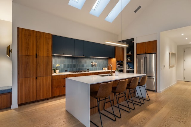 kitchen with brown cabinetry, visible vents, a sink, appliances with stainless steel finishes, and modern cabinets